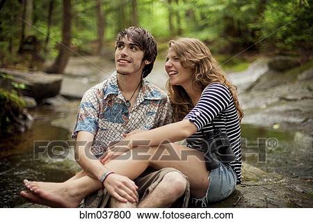 Couple sitting barefoot on boulders in forest View Large Photo Image Stock Image - Couple sitting barefoot on boulders in forest. Fotosearch