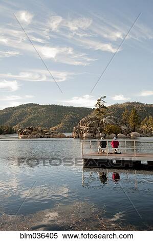 Couple sitting on wooden deck in remote lake View Large Photo Image Stock Photography - Couple sitting on wooden deck in remote lake. Fotosearch