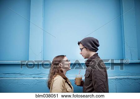 Stock Image - Couple standing near blue wall. Fotosearch