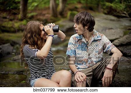 Stock Photo - Couple using binoculars on boulders in forest. Fotosearch