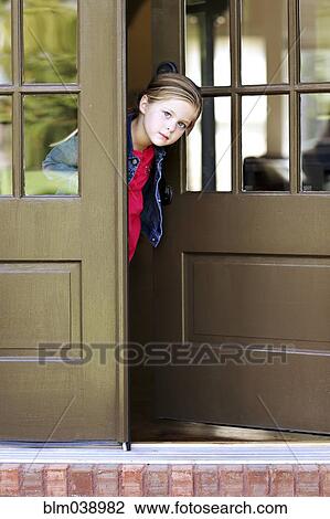Stock Image - Curious girl standing in doorway. Fotosearch