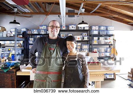 Stock Photo - Entrepreneurs hugging in workshop. Fotosearch