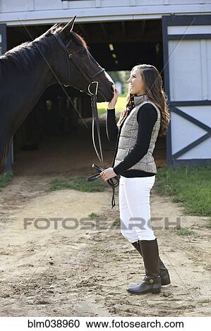 Equestrian woman petting horse at stable View Large Photo Image Stock Image - Equestrian woman petting horse at stable. Fotosearch