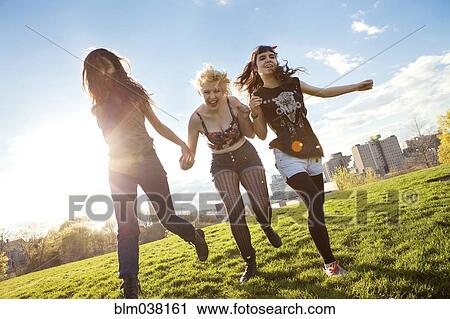 Stock Image - Friends holding hands in urban park. Fotosearch