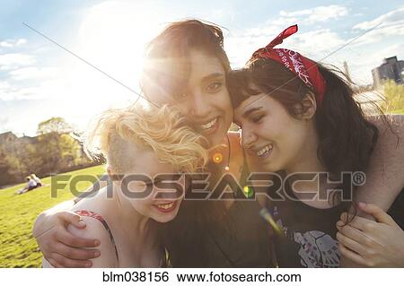 Friends hugging in sunny urban park View Large Photo Image Stock Photograph - Friends hugging in sunny urban park. Fotosearch