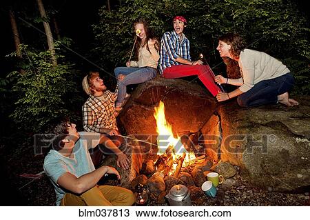 Friends roasting marshmallows over forest campfire View Large Photo Image Stock Image - Friends roasting marshmallows over forest campfire. Fotosearch