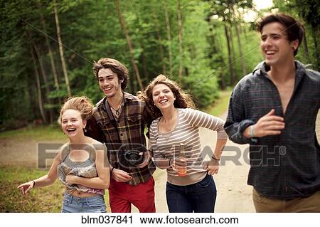 Stock Image - Friends running on dirt path in forest. Fotosearch