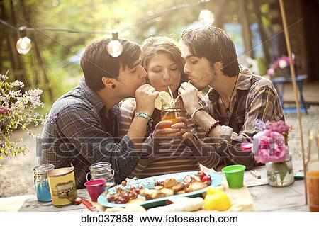 Stock Photo - Friends sharing soda at picnic table in forest. Fotosearch
