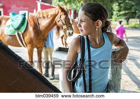 Frowning girl standing at post on ranch View Large Photo Image Stock Photo - Frowning girl standing at post on ranch. Fotosearch