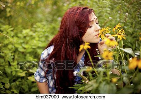 Stock Image - Gardener smelling flowers in field. Fotosearch