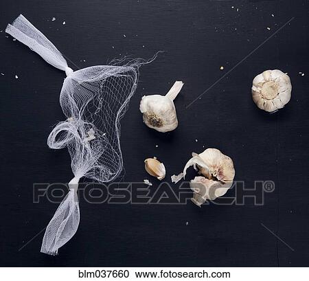 Stock Image - Garlic bulbs and netting on counter top. Fotosearch