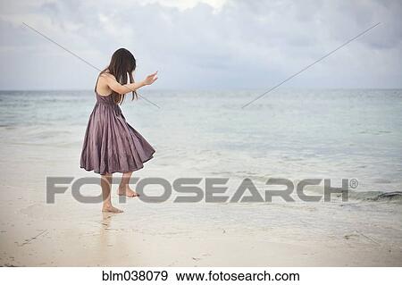 Girl dancing in waves on beach View Large Photo Image Stock Photo - Girl dancing in waves on beach. Fotosearch