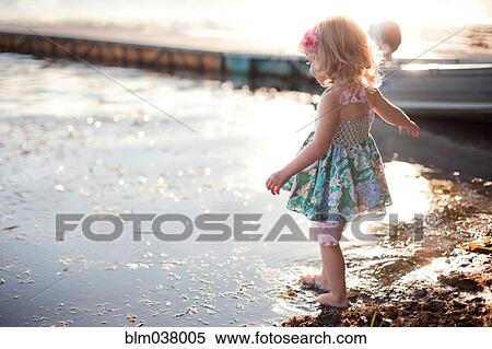 Stock Photography - Girl dipping toe in rural lake. Fotosearch