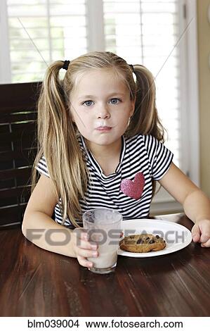 Picture - Girl eating cookies with milk mustache at table. Fotosearch