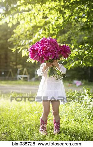 Stock Photo - Girl holding bouquet of flowers in backyard. Fotosearch