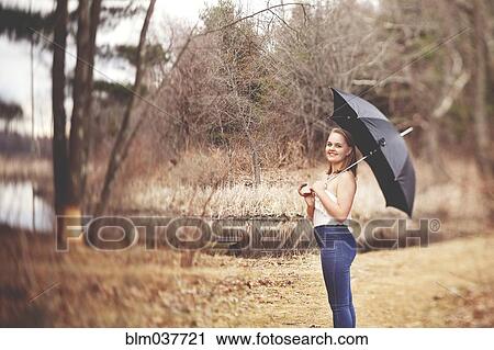 Stock Image - Girl holding umbrella in park. Fotosearch