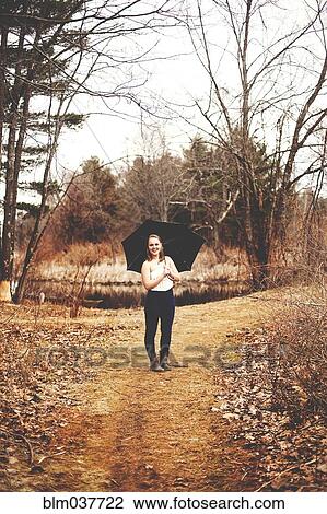Stock Image - Girl holding umbrella in park. Fotosearch