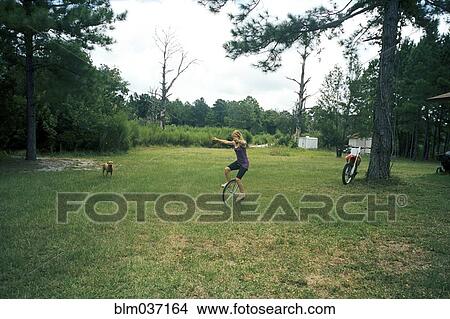 Picture - Girl playing on unicycle in field. Fotosearch