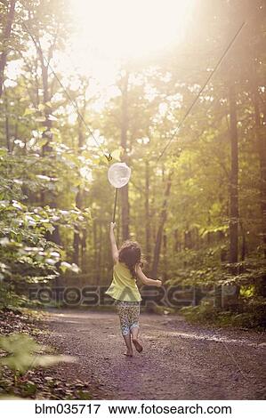 Stock Photo - Girl playing with butterfly net in forest. Fotosearch