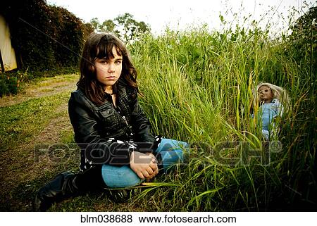 Stock Photo - Girl playing with doll in tall grass. Fotosearch