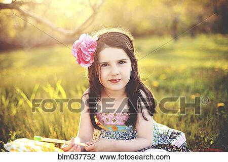 Stock Image - Girl playing with pinwheel in rural field. Fotosearch