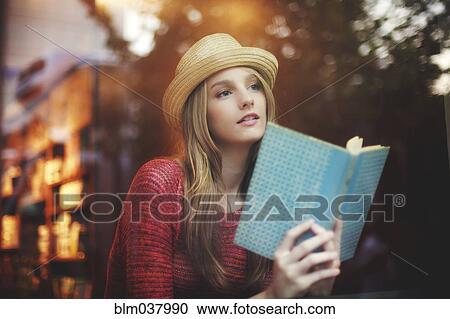 Stock Image - Girl reading book near window. Fotosearch