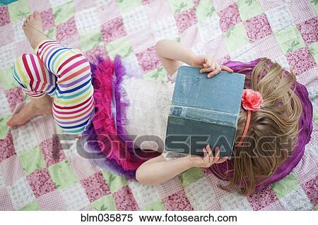 Stock Photography - Girl reading book on blanket. Fotosearch