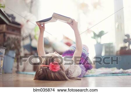 Girl reading book on living room floor View Large Photo Image Picture - Girl reading book on living room floor. Fotosearch