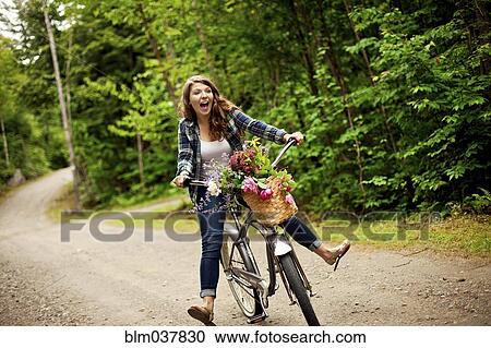 Stock Image - Girl riding bicycle on dirt path. Fotosearch