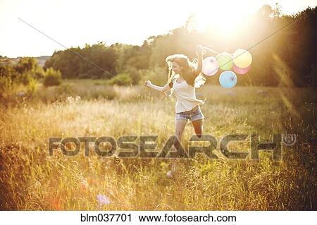 Girl running with balloons in sunny field View Large Photo Image Stock Image - Girl running with balloons in sunny field. Fotosearch
