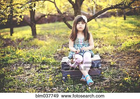 Stock Photo - Girl sitting on crate in orchard. Fotosearch