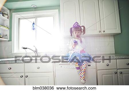 Girl sitting on kitchen counter View Large Photo Image Stock Photograph - Girl sitting on kitchen counter. Fotosearch