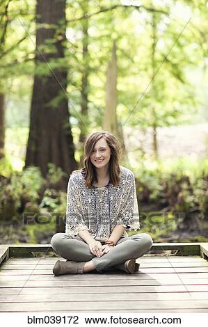 Girl sitting on wooden patio near tree View Large Photo Image Stock Image - Girl sitting on wooden patio near tree. Fotosearch