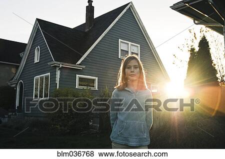 Stock Photo - Girl smiling near house at sunset. Fotosearch