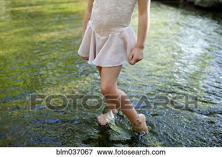 Stock Photo - Girl standing barefoot in pond. Fotosearch