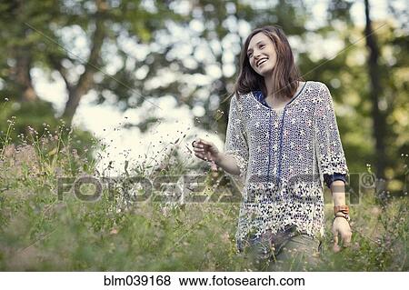 Stock Photo - Girl walking in tall grass in forest. Fotosearch