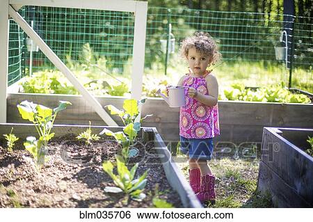 Girl watering plants in garden View Large Photo Image Stock Photograph - Girl watering plants in garden. Fotosearch