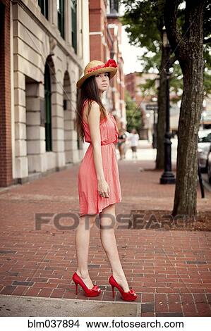Picture - Girl wearing straw hat and high heels on sidewalk. Fotosearch