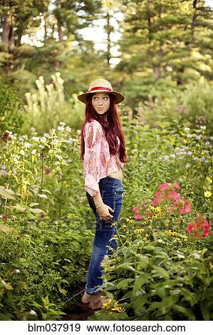 Stock Photo - Girl wearing straw hat in garden. Fotosearch