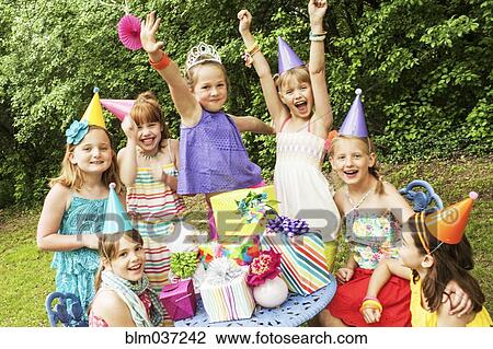 Stock Image - Girls cheering with gifts at birthday party. Fotosearch