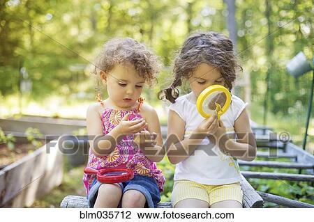 Girls examining garden plants with magnifying glass View Large Photo Image Stock Image - Girls examining garden plants with magnifying glass. Fotosearch