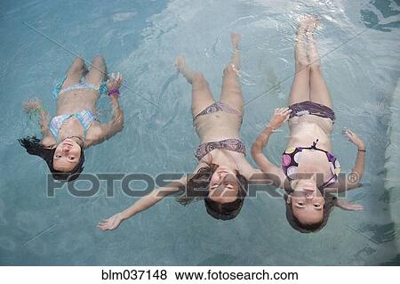 Stock Photo - Girls floating in swimming pool. Fotosearch