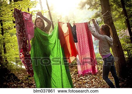 Girls hanging laundry on clothesline in forest View Large Photo Image Stock Image - Girls hanging laundry on clothesline in forest. Fotosearch
