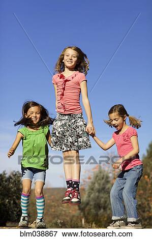 Stock Photo - Girls jumping for joy on wall. Fotosearch