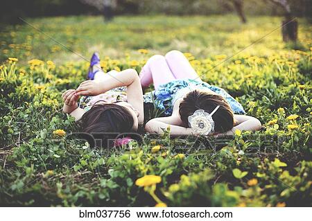 Stock Photograph - Girls talking and laying in field of flowers. Fotosearch