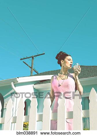 Stock Image - Glamorous woman in vintage clothing drinking cocktail. Fotosearch