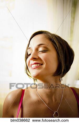 Stock Image - Glamorous woman smiling with eyes closed. Fotosearch