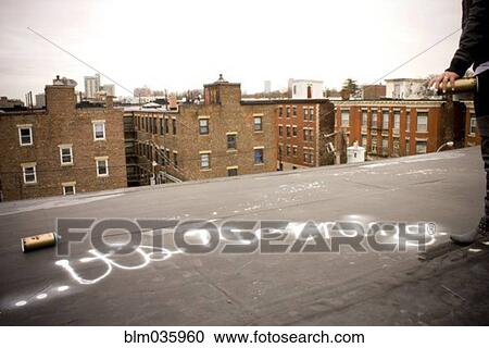 Graffiti artist spray painting on urban rooftop View Large Photo Image Stock Image - Graffiti artist spray painting on urban rooftop. Fotosearch