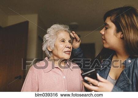 Stock Photograph - Granddaughter applying makeup on grandmother. Fotosearch
