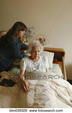 Stock Photograph - Granddaughter helping grandmother into bed. Fotosearch